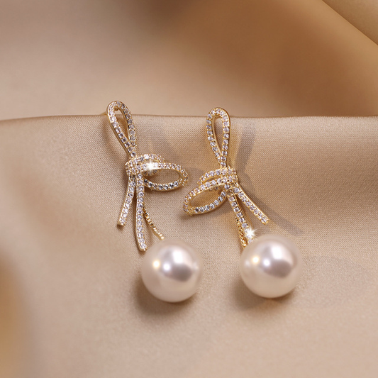 Pearl earrings with a glossy gold bow